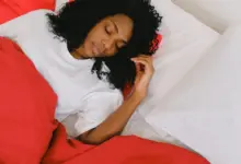 Mulher dormindo de lado na cama, com a cabeça apoiada no travesseiro